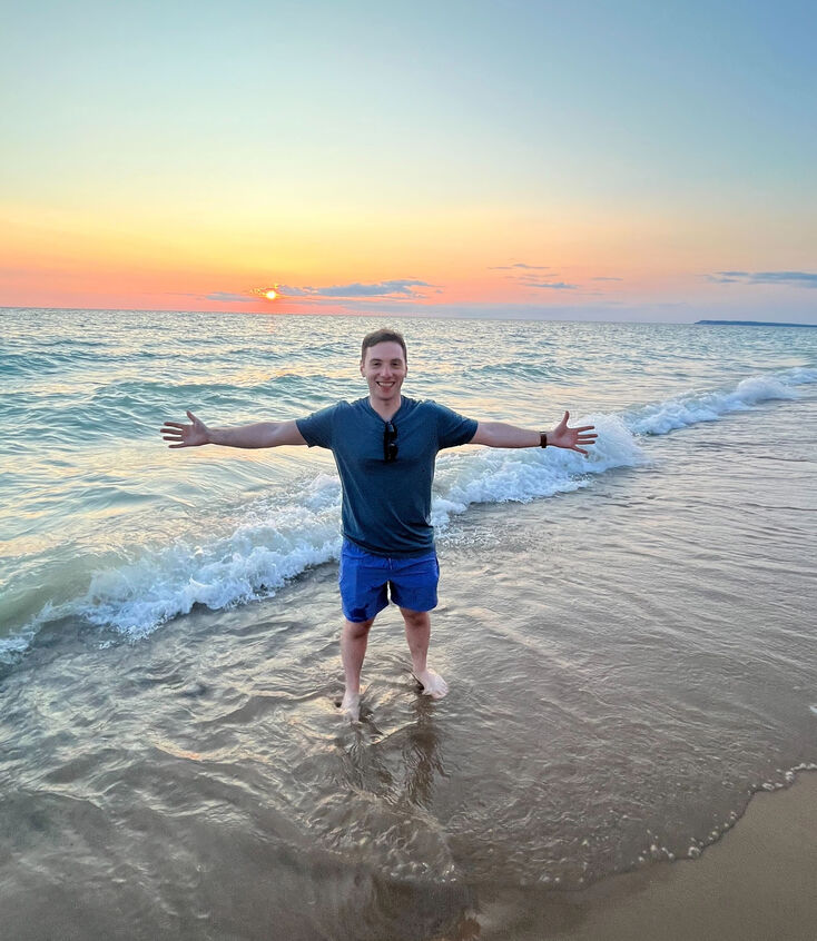 Man standing on the beach at sunset with arms out